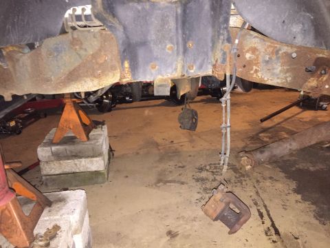 1994 Ford Bronco - Vehicle frame and suspension parts are rusted and supported by jack stands.