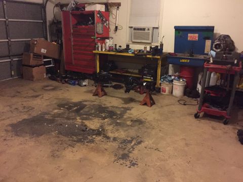1994 Ford Bronco - A cluttered garage scene shows tools, car parts, and storage units, with a prominent red toolbox and a workbench.
