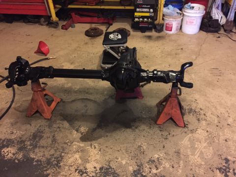 1994 Ford Bronco - Rear axle assembly supported by jack stands, with tools and storage in the background.
