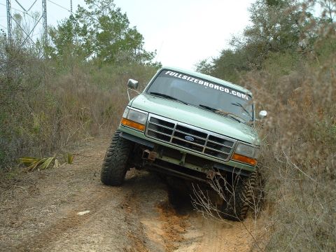 1995 Ford Bronco - This 1995 Ford Bronco is navigating a challenging off-road trail with steep inclines and loose dirt.
