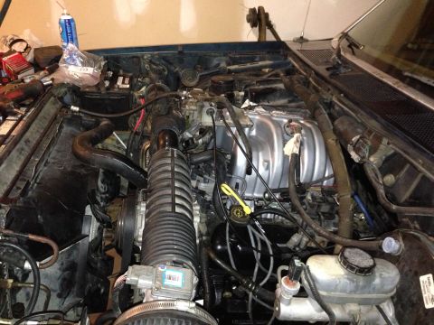 1994 Ford Bronco - The engine bay of a vehicle is shown with many parts and wiring. Some tools are also visible.