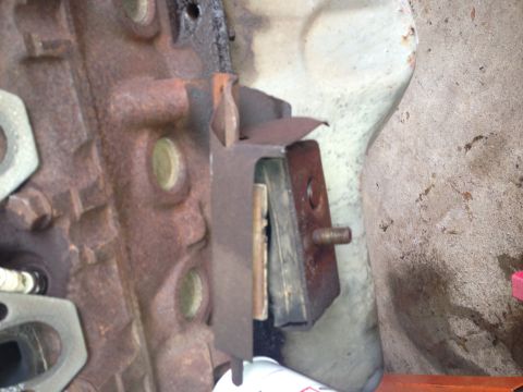 1994 Ford Bronco - Close-up of a corroded engine mount bracket on a cast iron block.