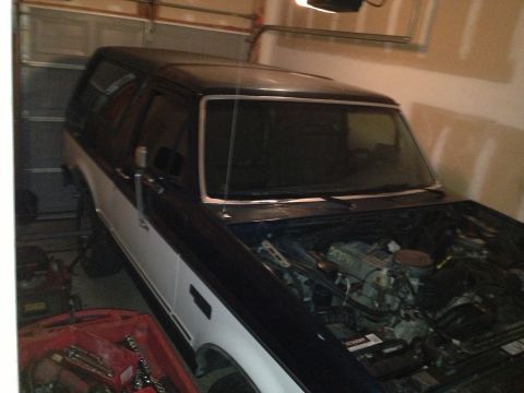 1994 Ford Bronco - Ford Bronco in garage with hood open, revealing the engine bay. It has a two-tone paint scheme.
