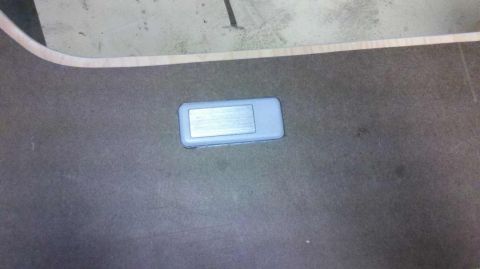 1982 Ford Bronco - A close-up view of a gray plastic part with a metallic insert against a dark background.