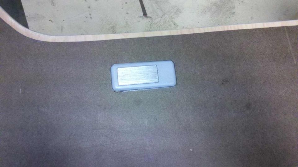 Rectangular gray plastic part with a silver metallic insert on a dark surface