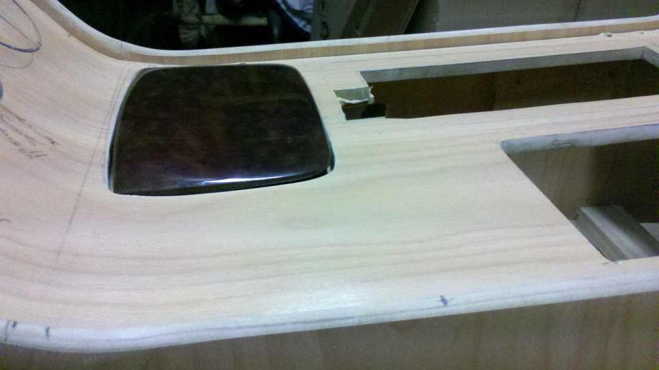 Unfinished wooden dashboard panel with a dark rectangular insert and cutouts for components