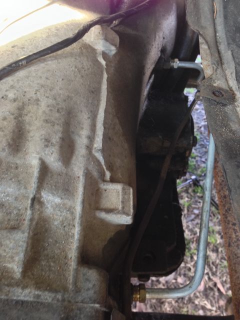 1979 Ford Bronco - A close-up view shows a portion of a vehicle's transmission housing with two metal brake lines attached. One line is silver and curves upwa…