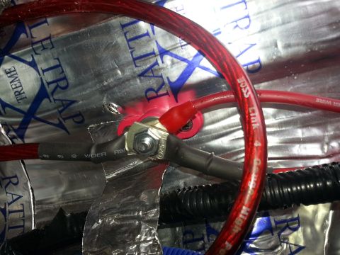 1994 Ford Bronco - Photo of a red audio power cable and fuse-link bolted to a grounding stud over foil sound-deadener.