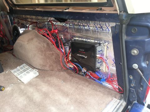 1994 Ford Bronco - Photo of a cargo-area car-audio install showing a Pioneer amplifier and bundled colored wiring over foil deadener.