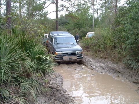 1995 Ford Bronco - This gray SUV navigates a muddy trail, with another vehicle following closely behind.