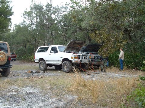 1995 Ford Bronco - Two SUVs are parked off-road with their hoods open, suggesting mechanical attention is needed.