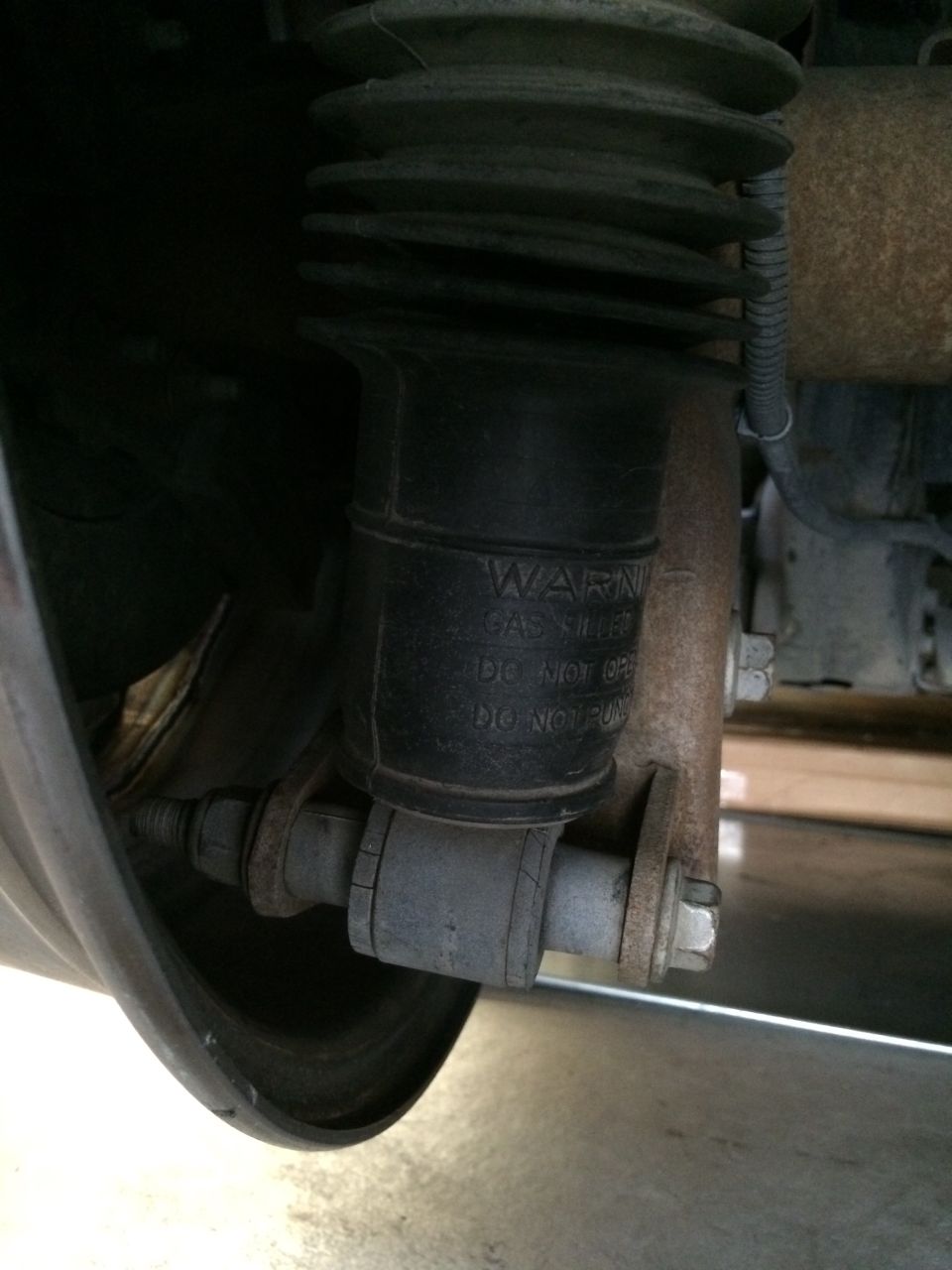Underside view of vehicle suspension showing rubber bellows air spring and lower control arm bolt