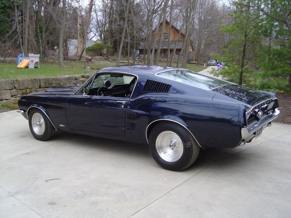 Dark blue 1967 Ford Mustang, rear passenger side view, parked on concrete.