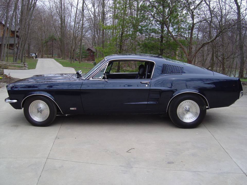 Dark blue 1967 Ford Mustang coupe, side view, parked on concrete.