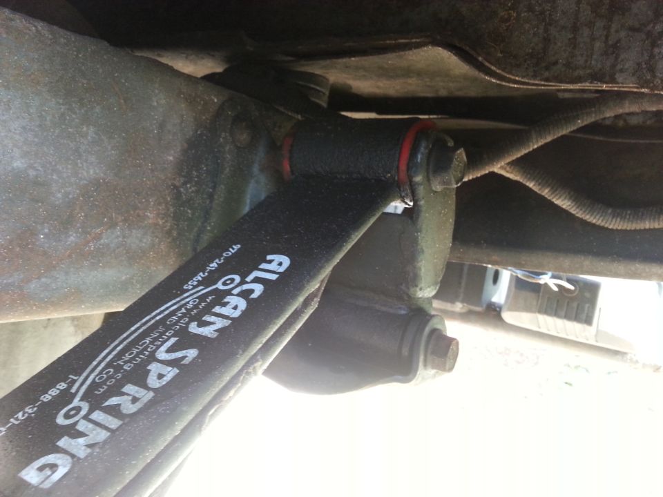 Close-up of Alcan leaf spring with white lettering on a vehicle underside.