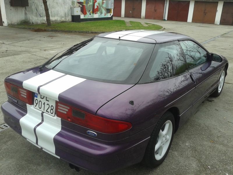 Purple 1994 Ford Probe with white racing stripes, rear passenger side view.