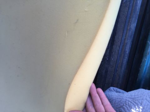 1996 Ford Bronco - A close-up view shows a hand holding a piece of yellow foam padding against a dark, ribbed surface, possibly part of a vehicle's interior o…