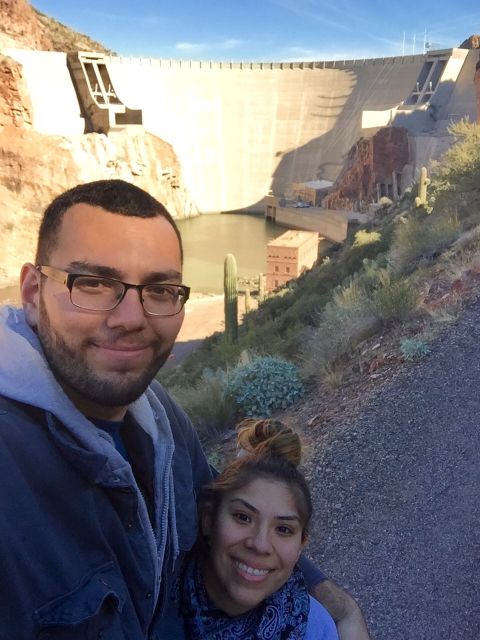 1996 Ford Bronco - A couple takes a selfie in front of a large dam with a reservoir and desert vegetation.