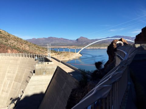 1996 Ford Bronco - A wide view of a large concrete dam with a lake and a bridge in the background under a clear blue sky.