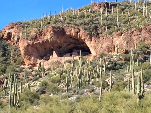 1996 Ford Bronco - A natural cave carved into a rocky hillside is visible, with ancient dwellings built inside. The surrounding landscape is arid, dotted with…