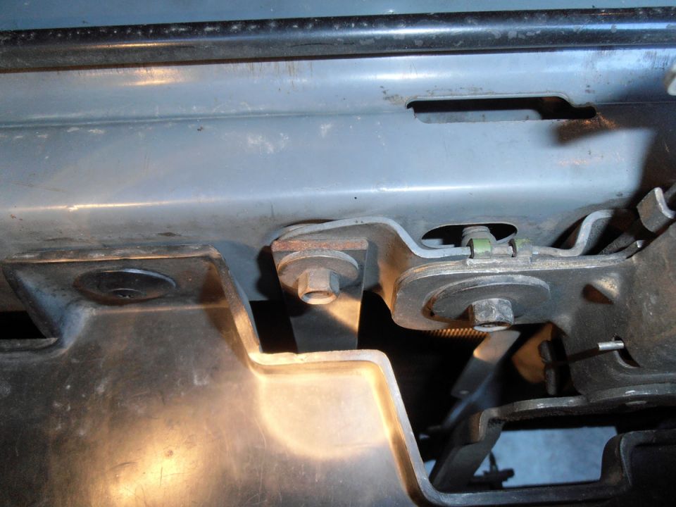 Vehicle frame mounting bracket with bolts and nuts, showing wear and rust.