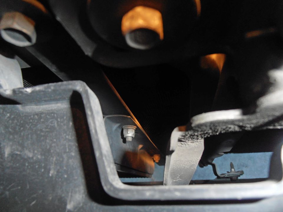 Close-up of a bolt and bracket on a vehicle's undercarriage.
