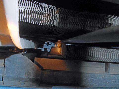 1990 Ford Bronco - A close-up view shows the ribbed fins of a vehicle's radiator and a portion of a hose secured by a clamp.
