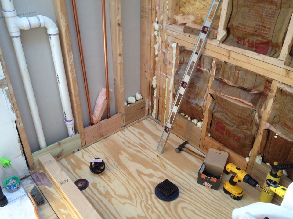 Bathroom under construction with plumbing, insulation, and tools.