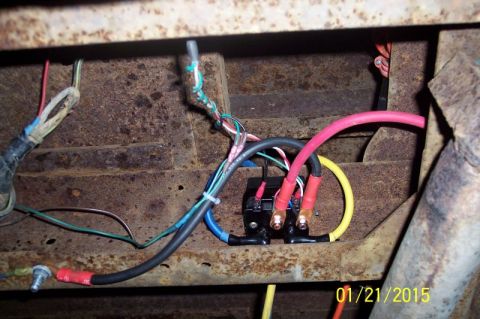 1973 Ford F-250 - A close-up view shows a black electrical relay box mounted to the rusty frame of a vehicle. Various colored wires, including thick red and…