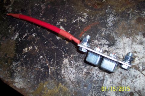 1973 Ford F-250 - A close-up view shows a red automotive wire connected to a metal bar with three silver relays and several nuts and bolts. The background is…