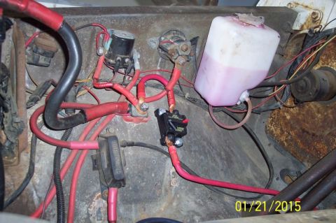 1973 Ford F-250 - The engine bay of a 1973 Ford F-250 shows a complex wiring system with a large black wire bundle, a pink fluid reservoir, and several elect…