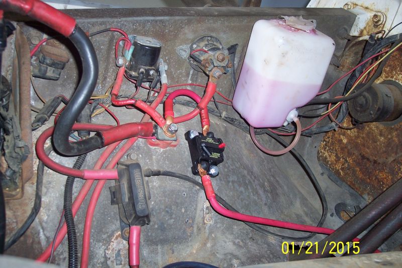 Engine bay wiring, fuse block, circuit breaker, and fluid reservoir in a 1973 Ford F-250.