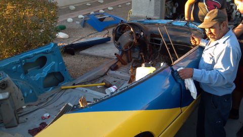 1995 Ford Probe - A man in a blue shirt and baseball cap wipes down the interior of a disassembled car with blue and yellow paint. The car's interior is expo…