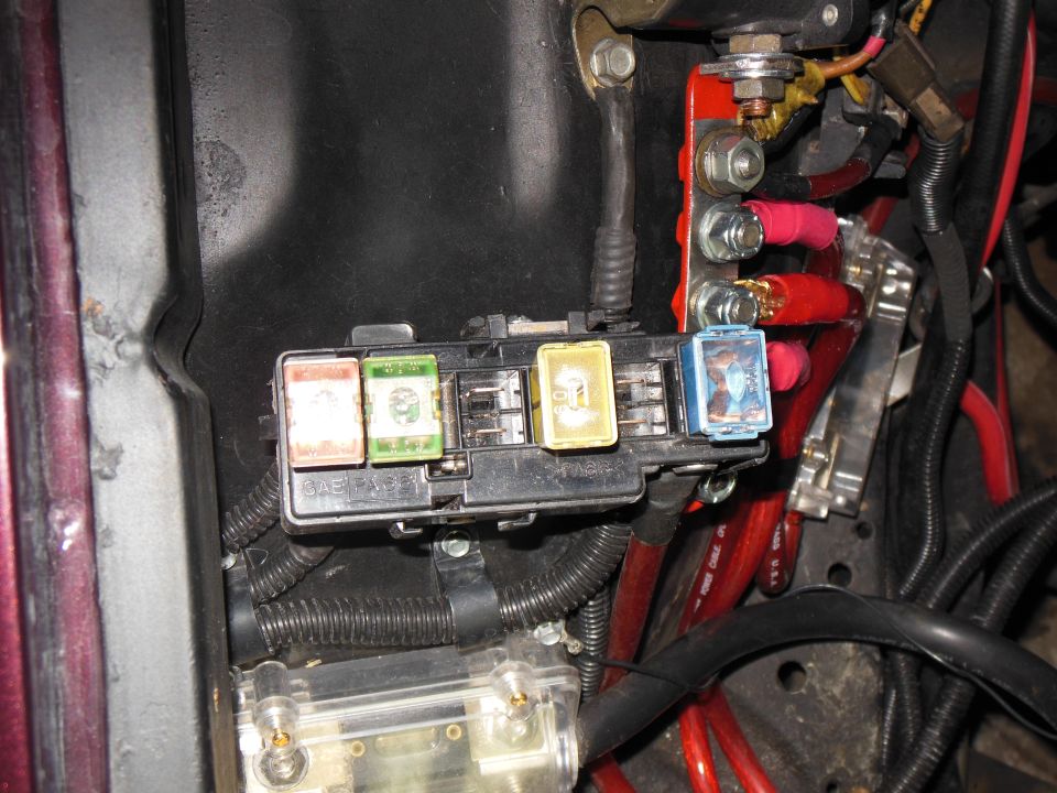 Maxi-fuse block with colored cartridge fuses mounted on an engine-bay inner fender