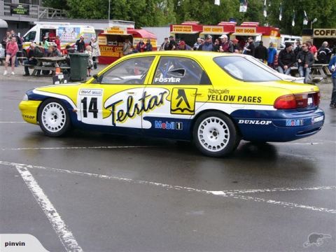 1993 Mazda MX-3 - Race car with 'Telstar' and 'Yellow Pages' sponsorship on the side, parked on a wet track.