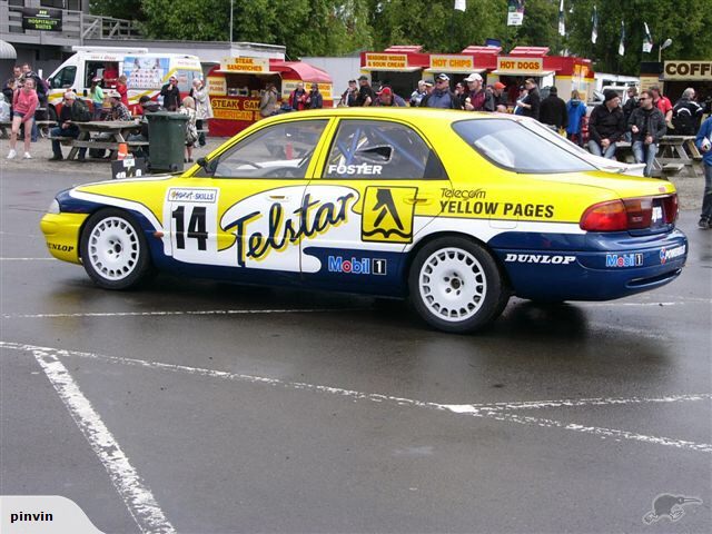 Side view of a race car with number 14 and 'Telstar' livery, yellow and blue colors, Dunlop tires