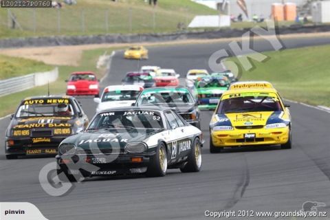 1993 Mazda MX-3 - Multiple race cars compete on a paved track, with spectators visible in the background.