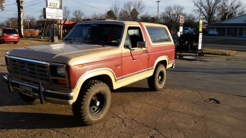 1986 Ford Bronco - Two-tone red and tan 1986 Ford Bronco parked outdoors.