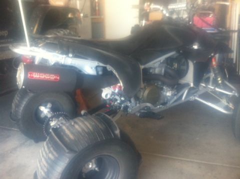 2005 Honda TRX 450 R - Quad bike with aftermarket exhaust and sand tires stacked in front. Some body panels are missing.