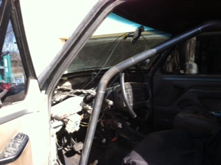 1995 Ford Bronco - The interior of a vehicle shows a roll cage installed, with the dashboard and steering wheel visible.