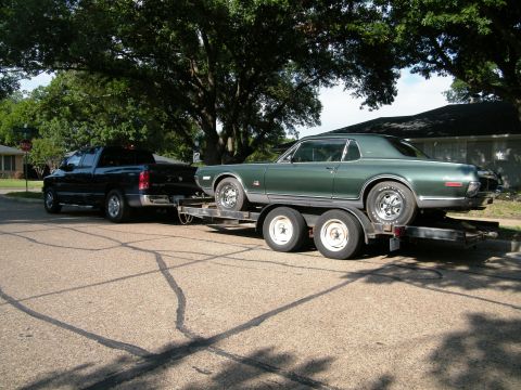 1968 Mercury Cougar - A green 1968 Mercury Cougar is loaded onto a trailer, ready for transport by a black pickup truck.