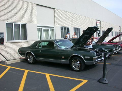 1968 Mercury Cougar - A row of classic cars, including a 1968 Mercury Cougar, are displayed with hoods up.