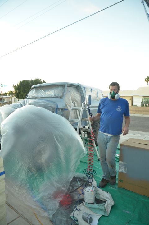 1979 Ford Bronco - A man in a respirator prepares to paint a 1979 Ford Bronco, which is covered in protective plastic sheeting.