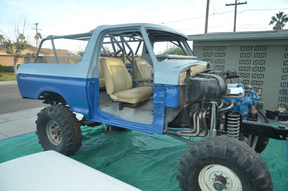 1979 Ford Bronco with roll cage, missing doors and hood, in blue and gray primer
