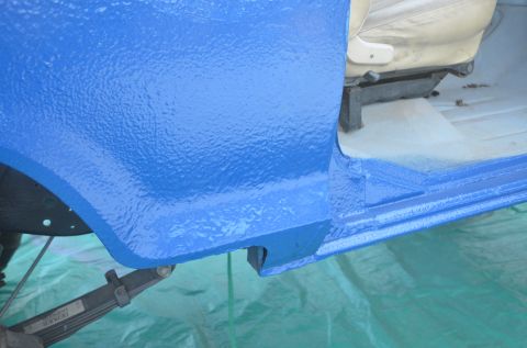 1979 Ford Bronco - Close-up of a vehicle's blue textured door sill and interior, with a beige seat visible.