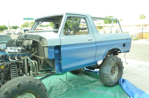 1979 Ford Bronco - This unfinished Ford Bronco, likely from the late 1970s, is undergoing modifications with a roll cage and large tires.