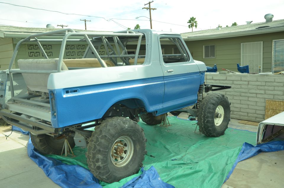 Modified 1978 Ford Bronco with roll cage, lifted suspension, and large tires, undergoing work