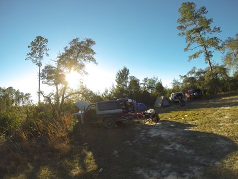1995 Ford Bronco - A campsite scene with a Ford Bronco, tents, and other vehicles under a clear blue sky.