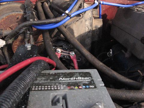 1994 Ford Bronco - Close-up view of a vehicle's engine bay, focusing on the battery and associated wiring and hoses.