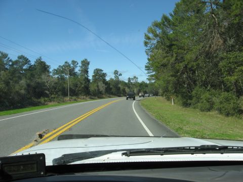 1994 Ford Bronco - View from inside a vehicle driving on a highway with a black SUV ahead and other cars in the distance.